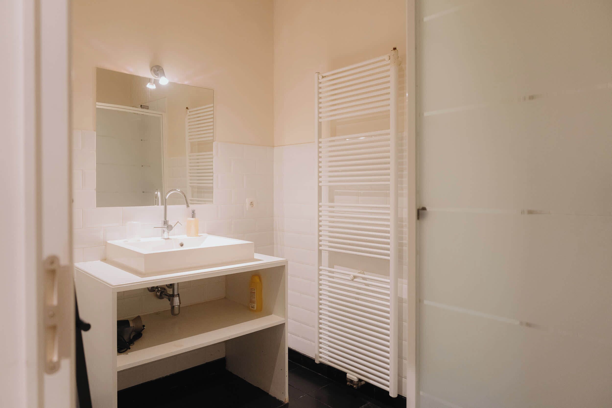 Een badkamer met een wit wastafelmeubel, spiegel en handdoekhouder.