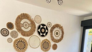 Een eethoek met een houten tafel, zwarte stoelen en diverse geweven wanddecoraties.