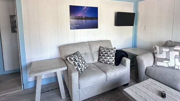 A cozy living room with a sofa, a coffee table, and a TV mounted on the wall.