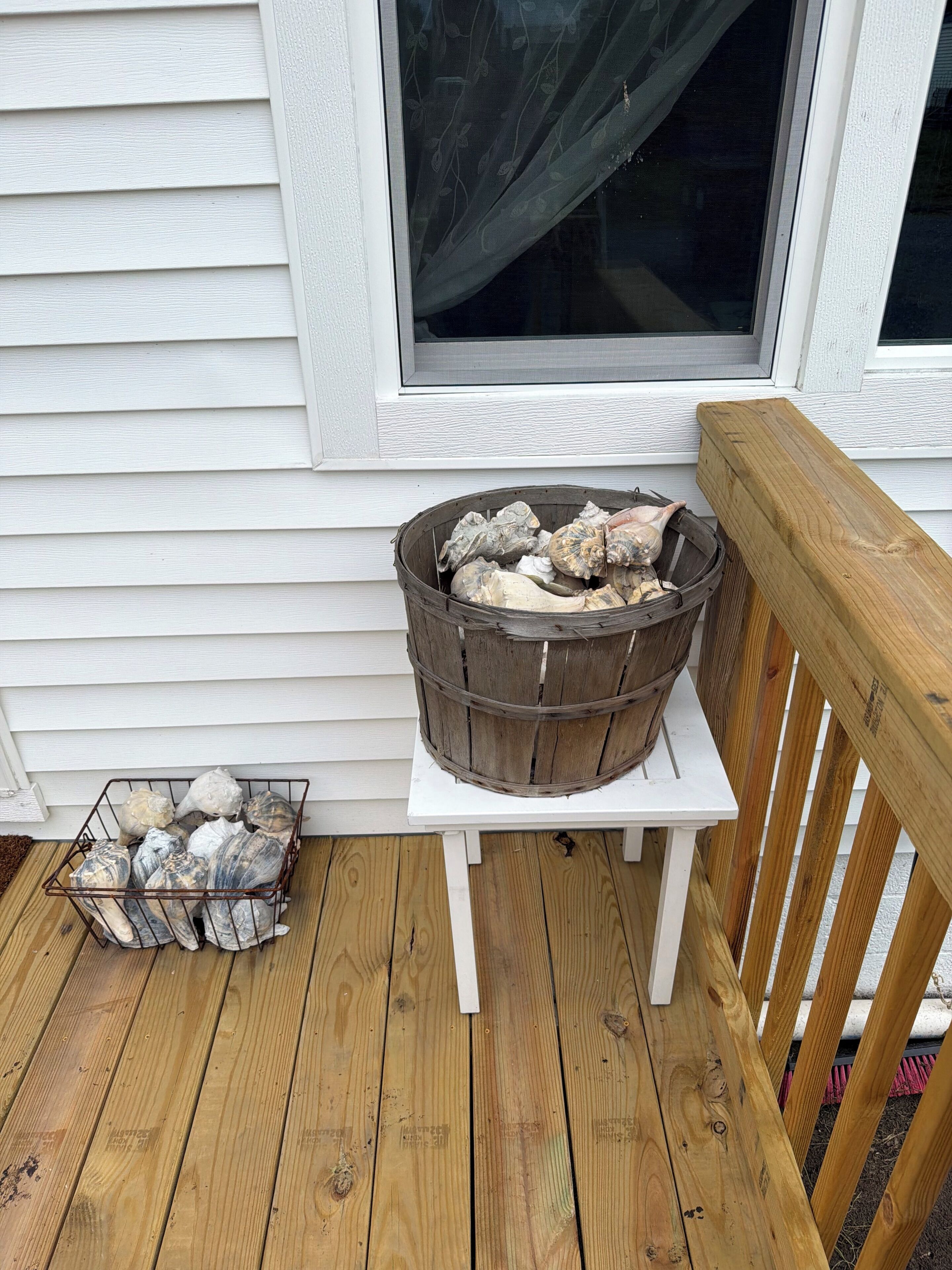 A wooden deck with a metal basket and a wooden crate filled with rocks.