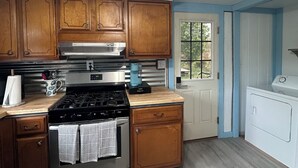 A kitchen with wooden cabinets, a stainless steel stove, and a washing machine.