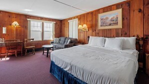 Ein Zimmer mit einem großen Bett, einem Schreibtisch mit Stuhl, einer Couch und zwei Wandlampen.
