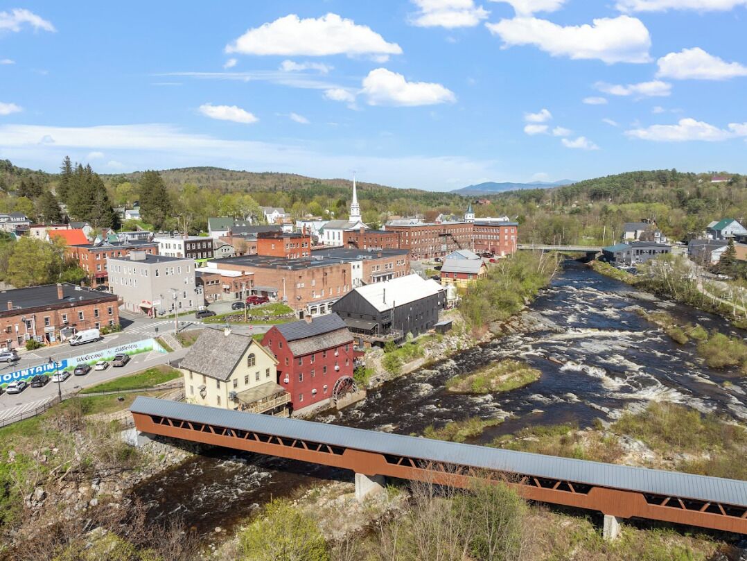 A town with a river, buildings, and a bridge.