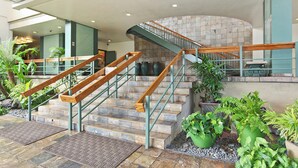 Un escalier avec des rampes en bois et des marches en pierre, entouré de plantes en pot.