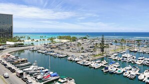 Un port de plaisance où sont amarrés de nombreux bateaux, une plage de sable et un ciel bleu azur.
