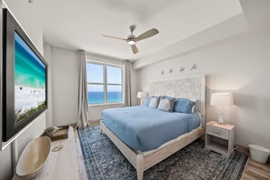 Ein Schlafzimmer mit einem Bett, einem Deckenventilator, einem Fernseher, einem Fenster und einem Nachttisch.