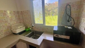 Una cocina con ventana, un fregadero, un escurreplatos y un electrodoméstico negro.