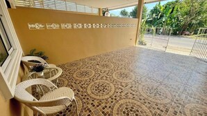 Un espacio de estar al aire libre cubierto con suelo estampado, sillas de mimbre y una pared decorativa.