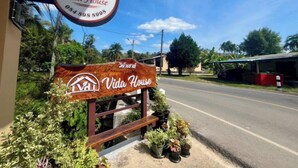 Un letrero de madera con la inscripción 'Vida House', rodeado de plantas en macetas.