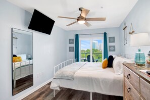 Ein Schlafzimmer mit einem Bett, einem Deckenventilator, einem an der Wand montierten Fernseher und Blick ins Freie.