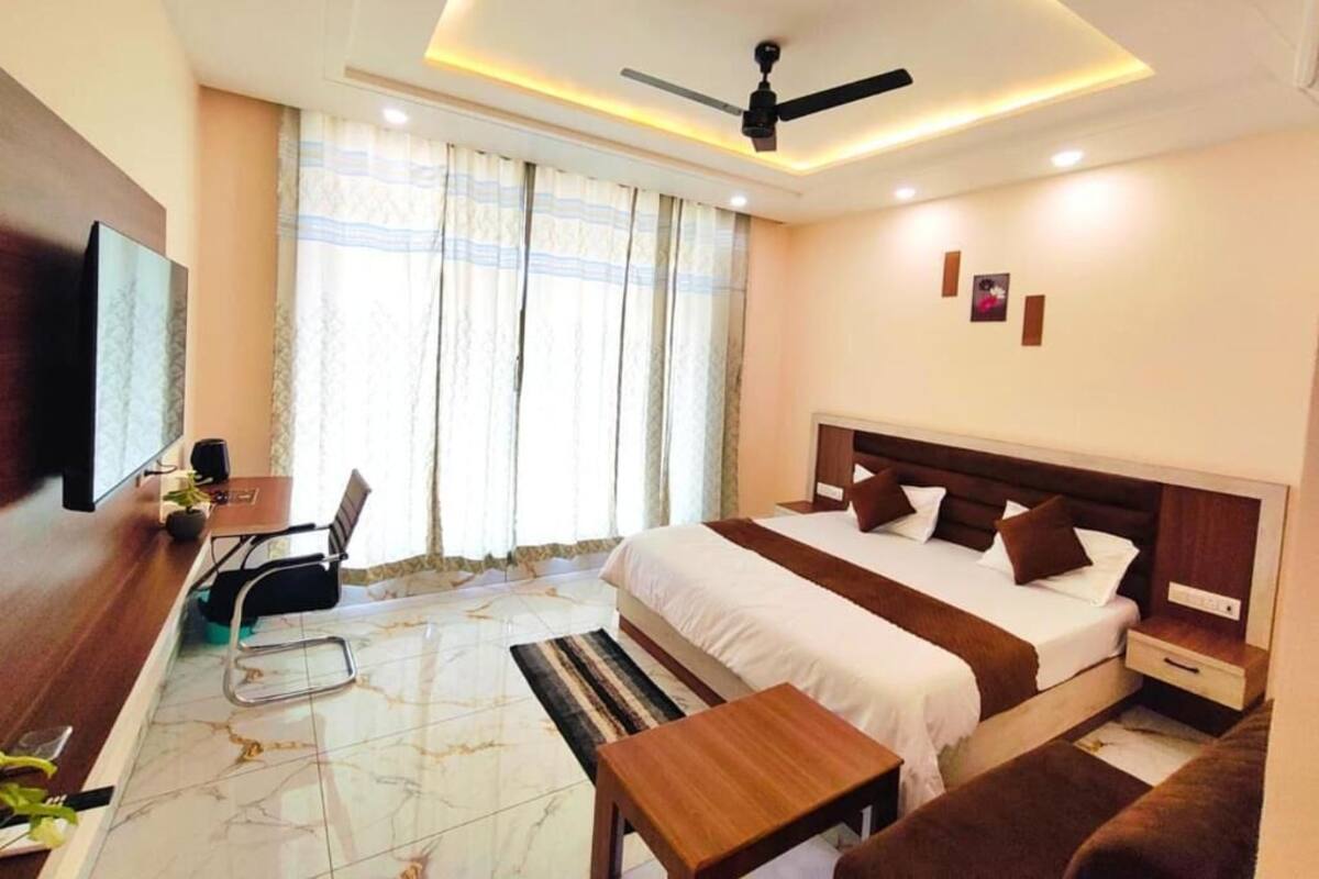 A hotel room with a bed, bedside tables, a desk with a chair, a TV, and a ceiling fan.