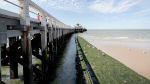 A pier extending into the water with a building at the end, a sandy beach, and a clear sky. - Beautiful apartment for 7 people with WIFI, TV and terrace (Blankenberge)