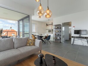 Un salon moderne comprenant un canapé, une table basse et un coin repas avec des chaises et une table.