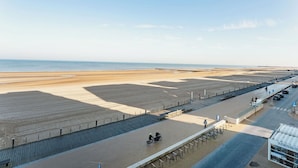 Een promenade aan het strand met een voetpad, een parkeerplaats en uitzicht op zee.