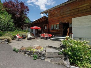 Un bâtiment en bois doté d’un patio comprenant des tables et des chaises, un espace extérieur aménagé pour s’asseoir et un parasol à l’effigie de Coca-Cola.