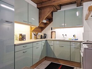 Een keuken met lichtgroene kastjes, een houten plafond en een betegelde spatwand.