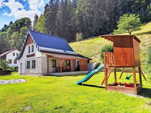 A chalet with a stone facade, a blue roof, and a wooden play structure with a slide. - Stunning private villa for 12 guests with WIFI, hot tub, patio, pets allowed and panoramic view (Dvůr Králové Nad Labem)