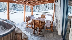Eine hölzerne Terrassenanlage im Freien mit Whirlpool, Holztischen und Bänken.