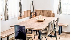 Ein Essbereich mit Holztisch, Stühlen und einer Gitarre an der Wand.