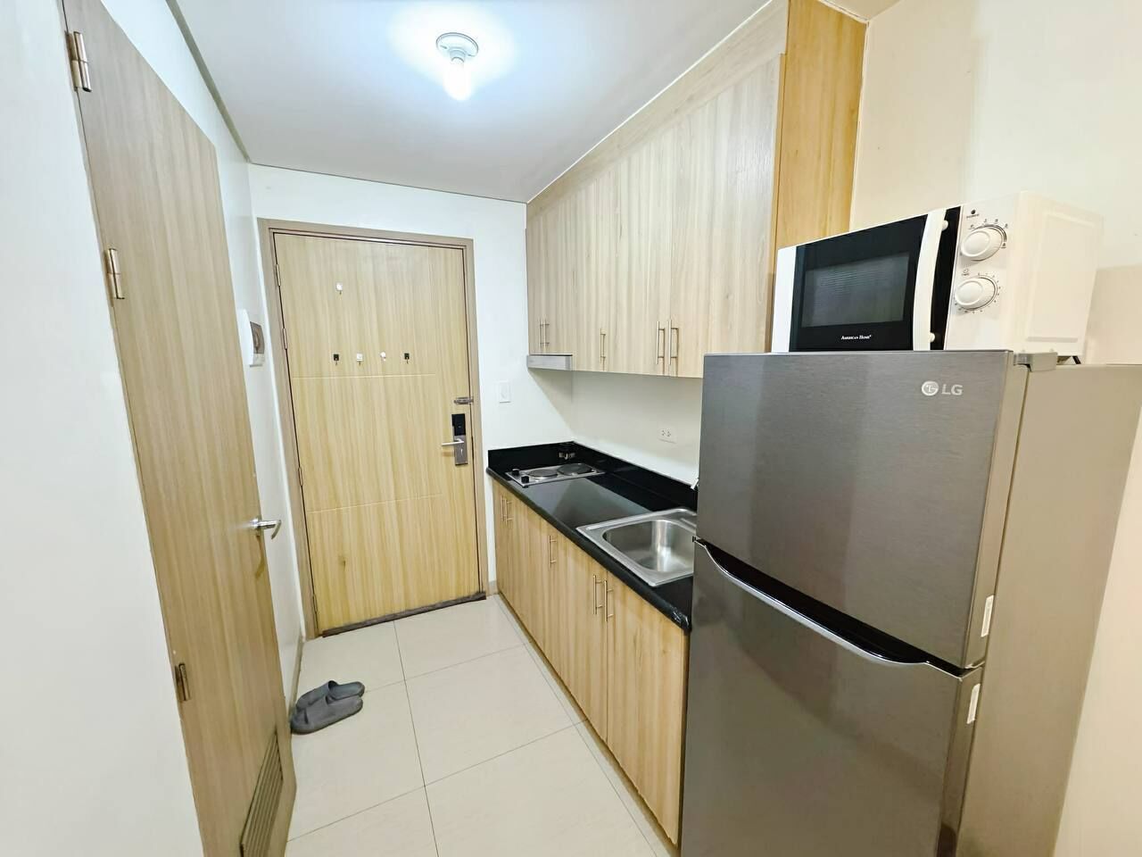 A compact kitchen with a refrigerator, microwave, and sink.