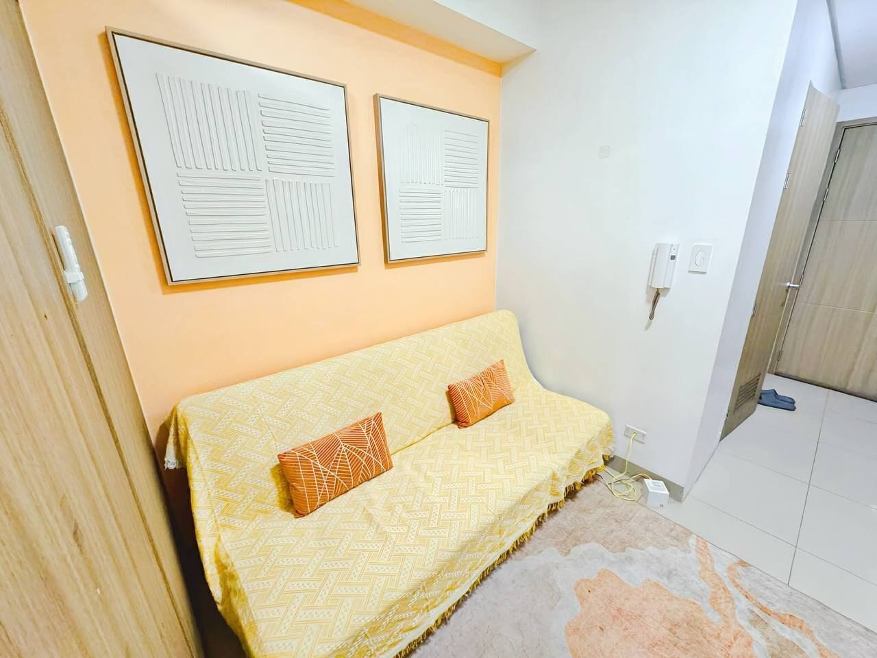 A bedroom with a bed, two wall-mounted artworks, and a door leading to another room.