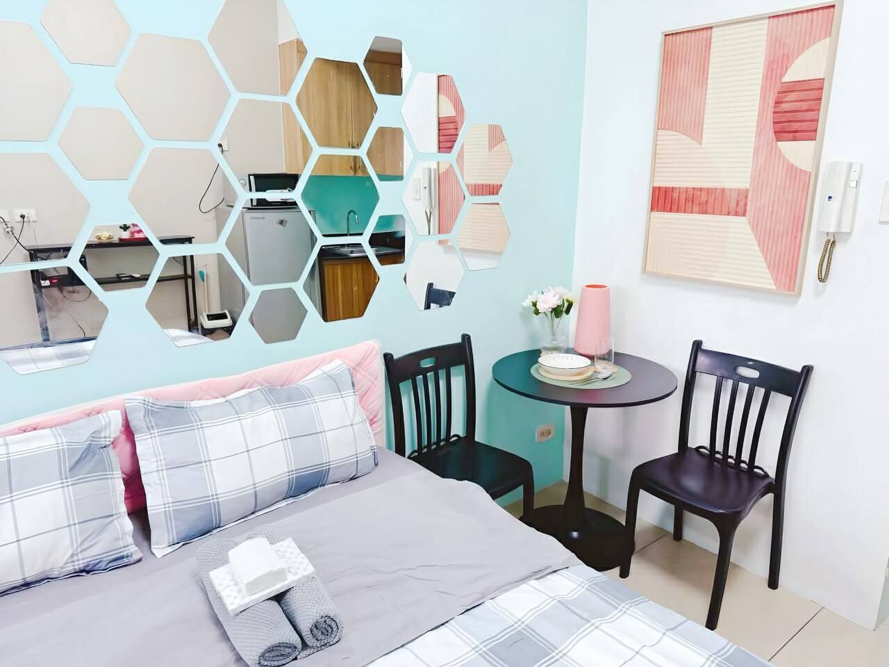 Un dormitorio con una cama, dos sillas, una mesita redonda, un espejo y una obra de arte en la pared.