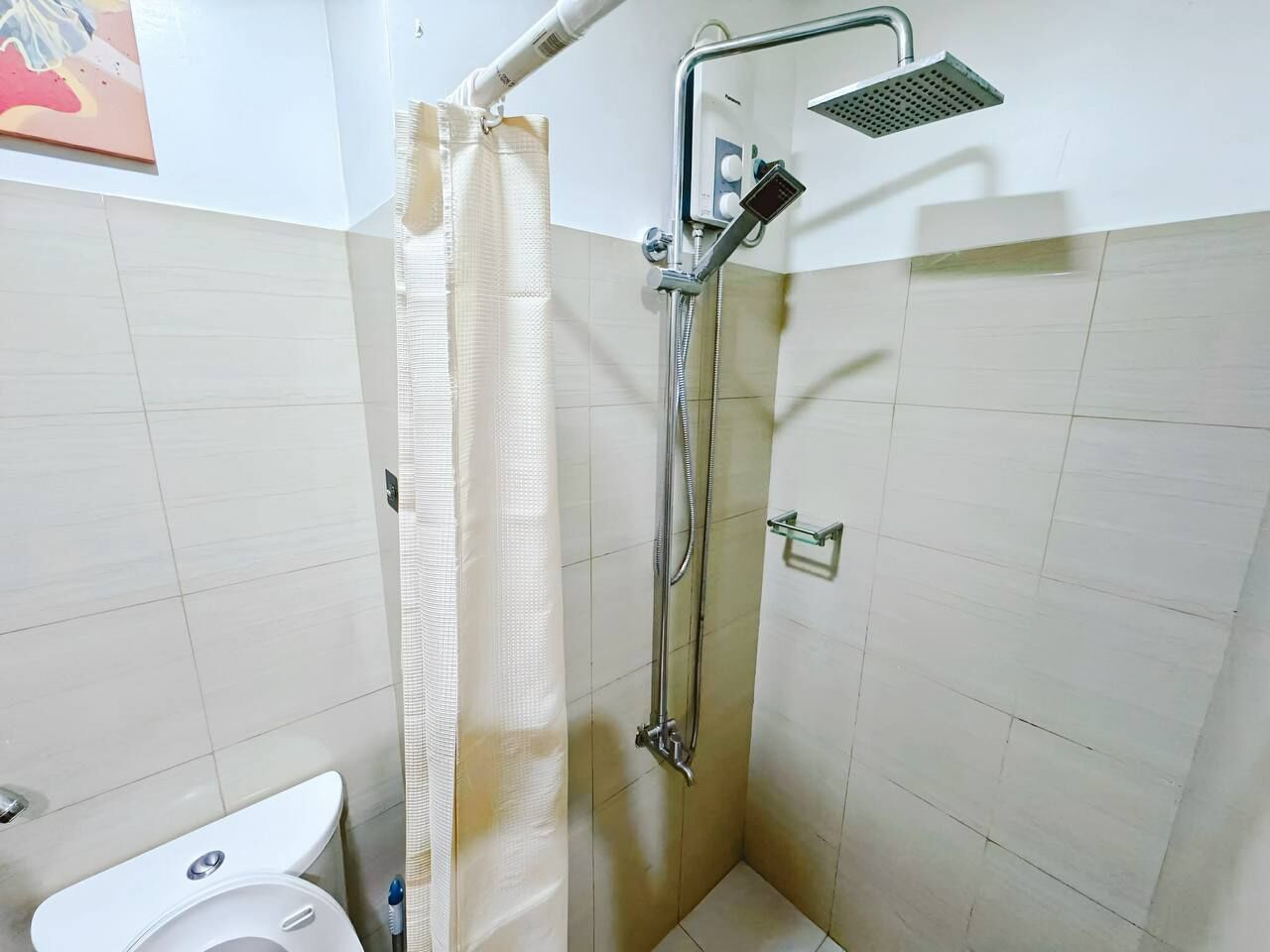 A shower with a handheld showerhead, a glass shower tray, and a curtain.