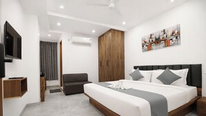 A modern bedroom with a large bed, a television, an air conditioning unit, and a painting on the wall. - Click Hotel Gachibowli Hyderabad (Hyderabad)
