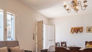 Une pièce meublée de mobilier en osier, dotée d’un lustre et d’une porte donnant sur une autre pièce.