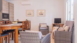 Une cuisine moderne équipée d’un four à micro-ondes, d’un four traditionnel, d’une table à manger, de chaises, de meubles en osier, d’un téléviseur et d’un lustre.