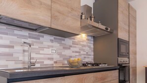 Une cuisine moderne avec un dosseret carrelé, des appareils électroménagers en acier inoxydable et des meubles de cuisine en bois.