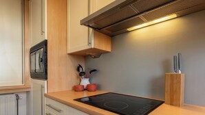 Una cocina moderna con placa de inducción integrada, armarios blancos y lavavajillas de acero inoxidable.