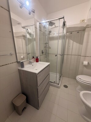 Une salle de bain moderne avec une douche à parois de verre, un lavabo blanc et des toilettes.