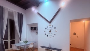 Una sala de estar moderna con un reloj de pared blanco, una mesa de comedor, sillas y un sofá.