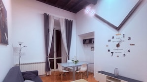 Una sala de estar con sofá, mesa de centro, mesa de comedor y un reloj de pared.