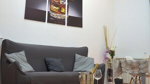 Una sala de estar con un sofá gris, una mesa de centro de madera y una obra de arte colgada en la pared.