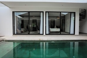 A modern house with a pool, large sliding glass doors, and a staircase. - D'Kenyeri Villa by Aayan (Tabanan)