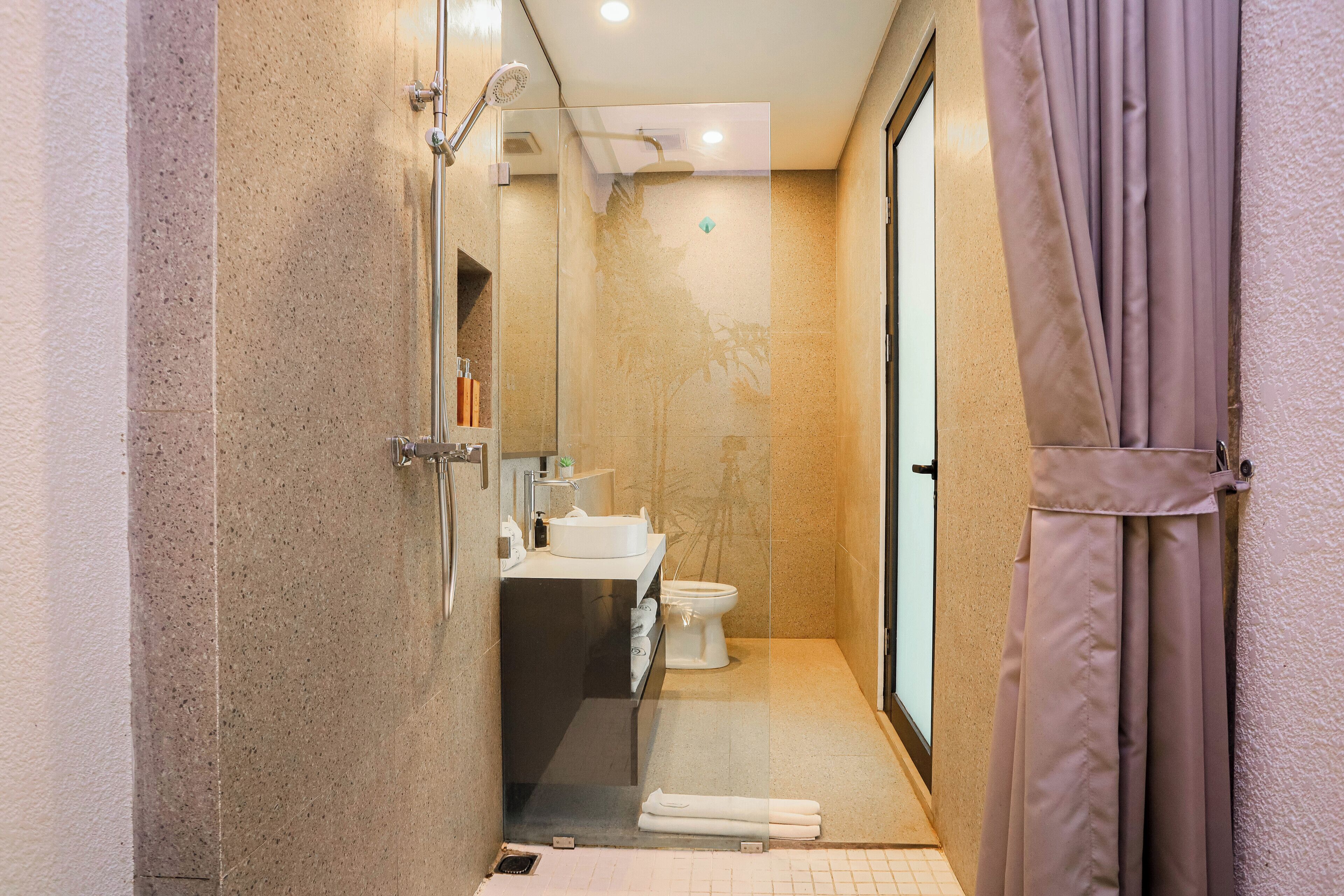 Un baño moderno con cabina de ducha de vidrio, un lavabo e inodoro.