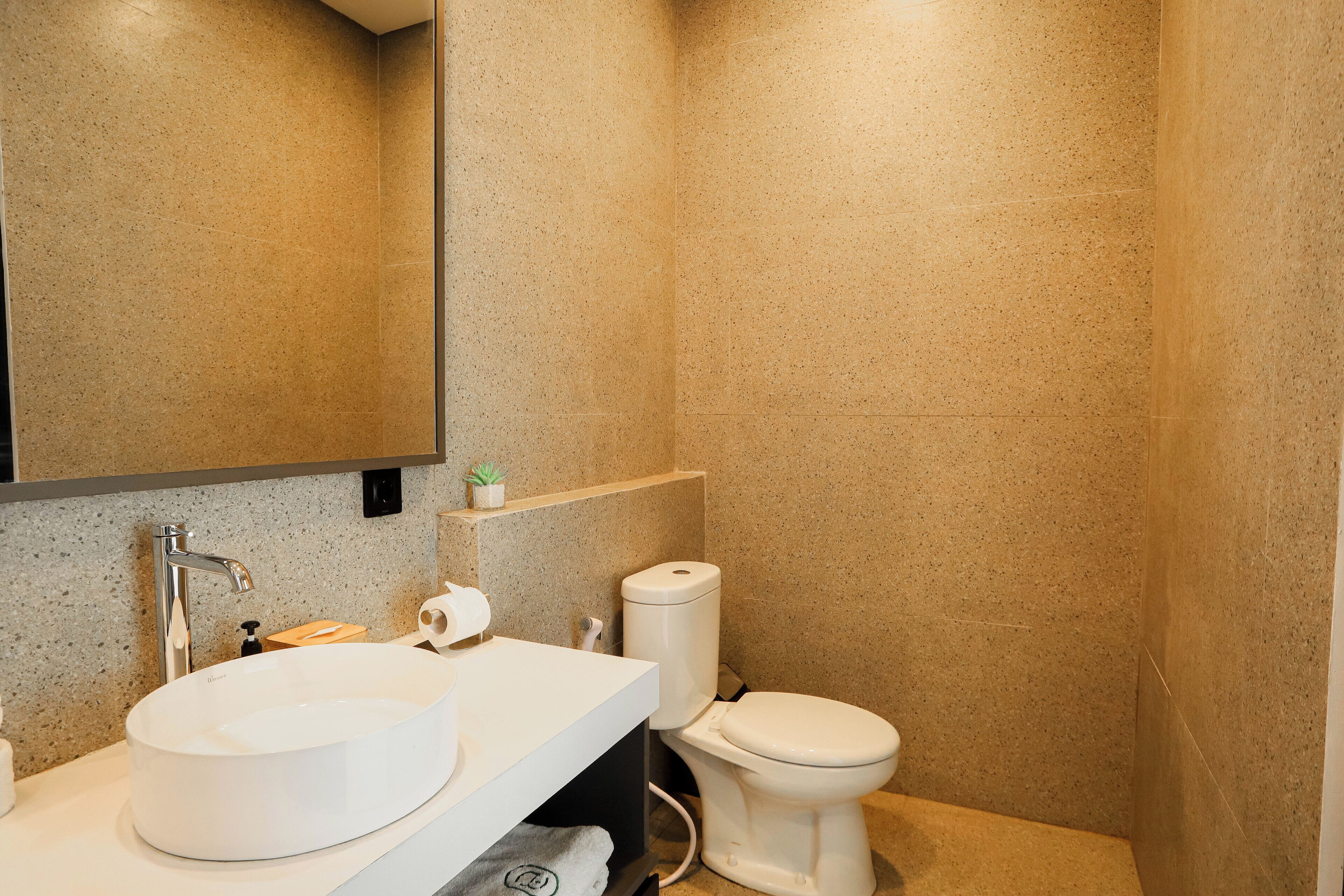 Une salle de bain avec un lavabo blanc, des toilettes et un miroir.