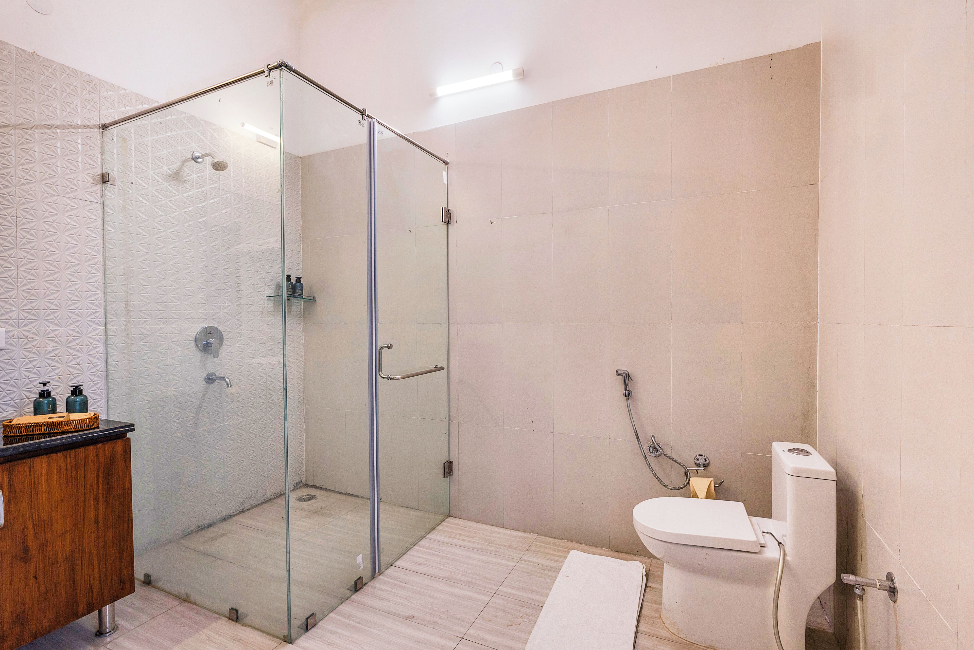 A modern bathroom with a glass-enclosed shower, a wooden vanity, and a toilet.