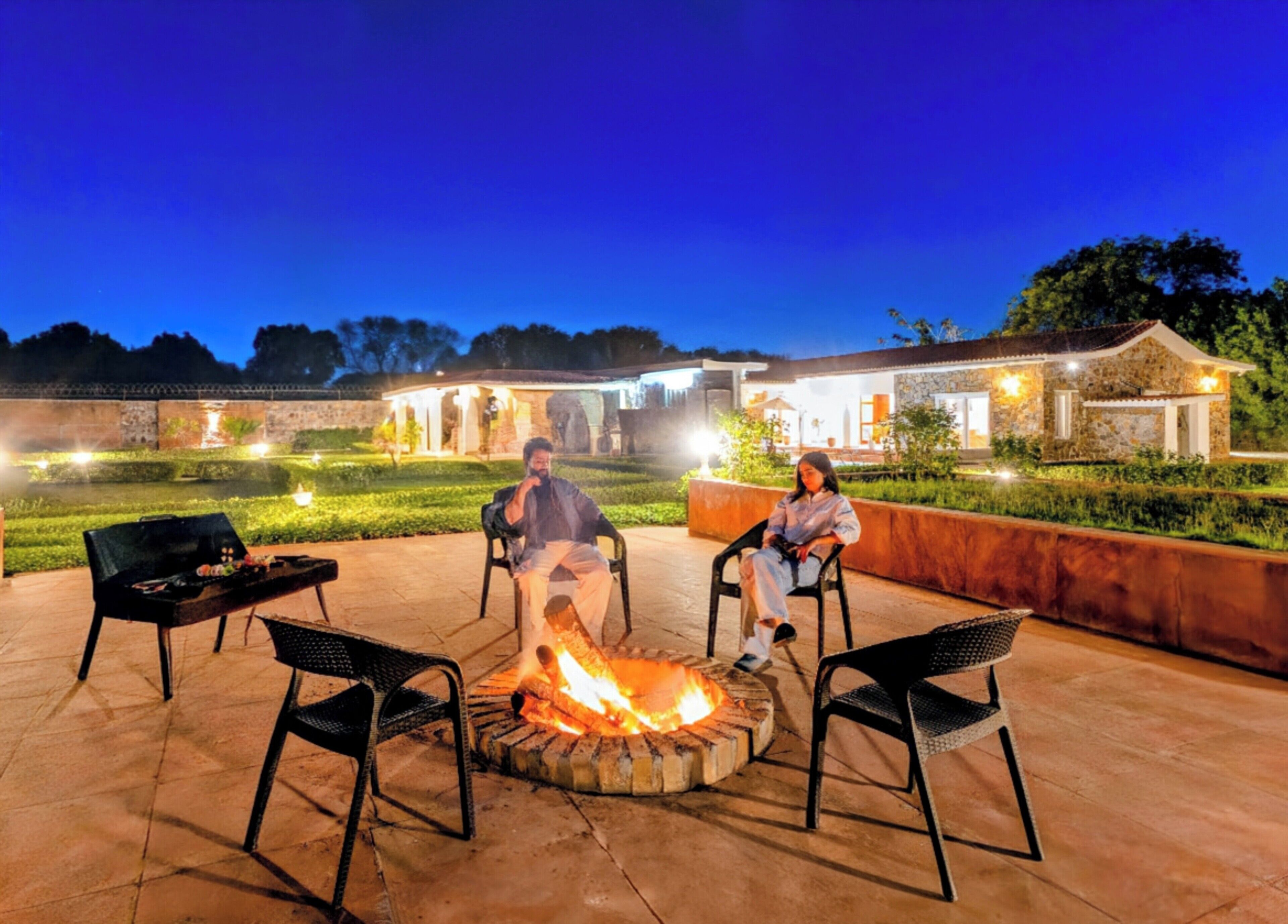 Un patio con una chimenea, mobiliario exterior y un edificio de piedra al fondo.