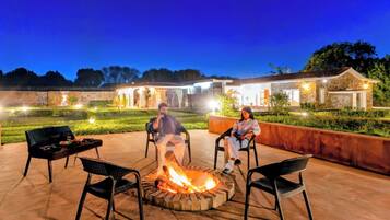 Un patio con una chimenea, mobiliario exterior y un edificio de piedra al fondo.