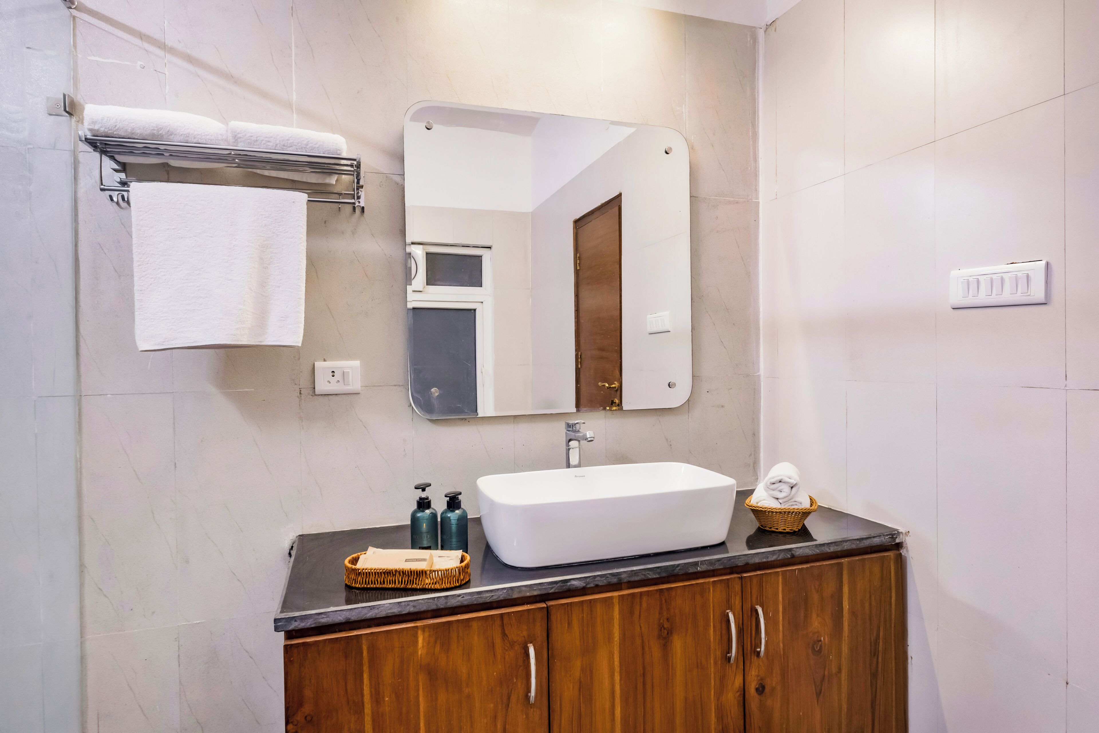 A bathroom with a white sink, wooden cabinets, a mirror, and a towel rack.
