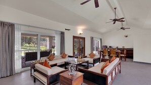 A spacious living area with multiple seating options, a dining area, and a kitchen. - ELIVAAS The Aravalli Reserve Isley Villa (Faridabad)