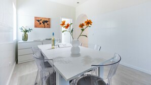 A modern dining area with a white table, clear chairs, and a vase with flowers. - Casa do Vale - in Paderne (Paderne)