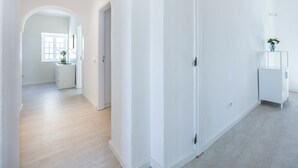 A spacious hallway with a white door, a small table with a vase, and a window with natural light. - Casa do Vale - in Paderne (Paderne)