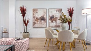 A modern dining area with a glass table, beige chairs, and abstract wall art. - Luxury Apartment in Cordoba Center. Plaza Doblas (Córdoba)