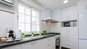A modern kitchen with white cabinets, a microwave, a coffee maker, and potted plants. - Luxury Apartment in Cordoba Center. Plaza Doblas (Córdoba)