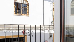 Un balcone con ringhiera in metallo, un cancello in legno e una finestra con inferriata decorativa.