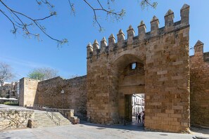 A historic stone gate with a central archway, a staircase leading up to it, and a clear blue sky above. - Genteel Home Almanzor (Córdoba)